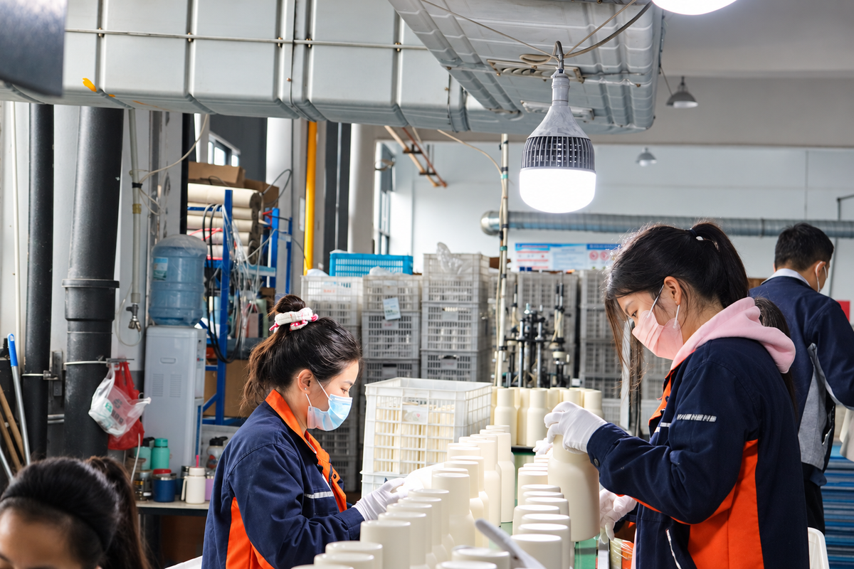 Team members inspecting and sorting drinkware at a worktable